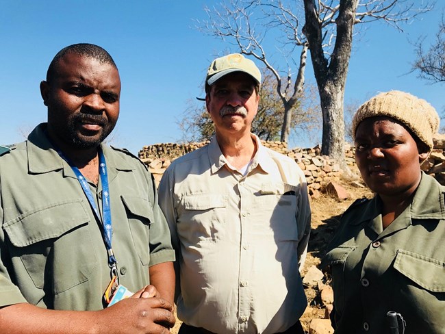 south africa trip two men and a woman posing for picture, the middle man has an NPS uniform while the other two have green uniforms from south africa's national parks