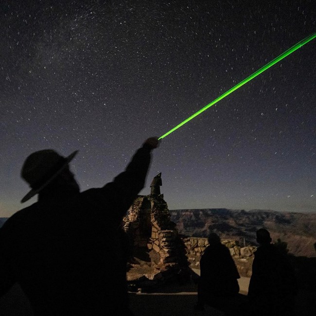 Ranger giving a constellation program A silhouetted ranger points a green laser at the stars