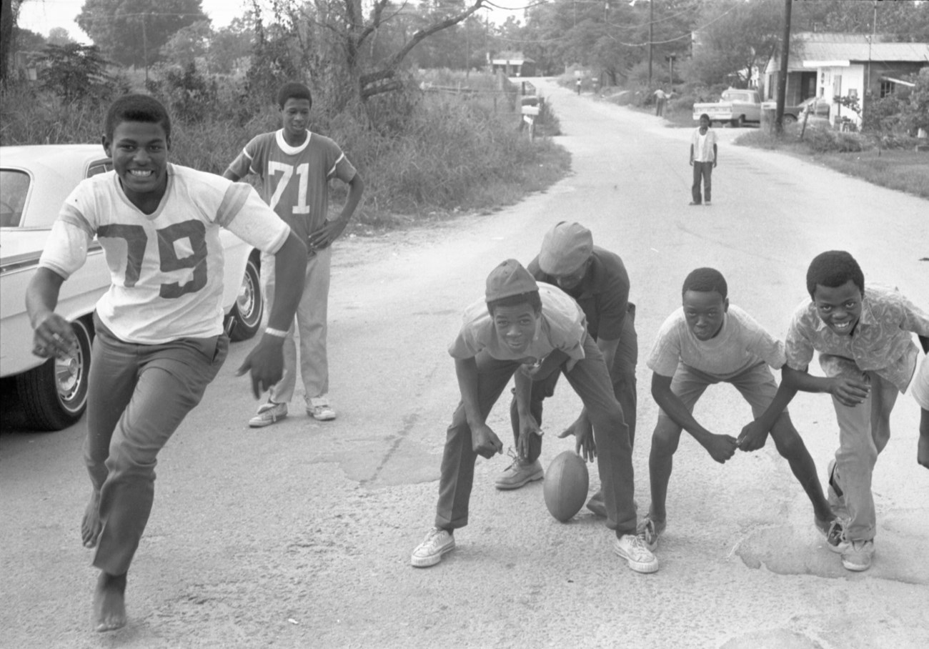 Boys playing football on a country road