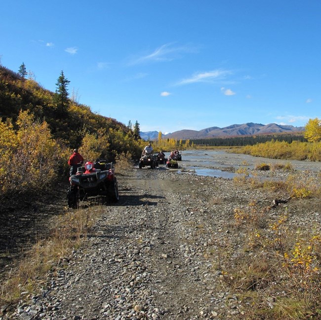 ATV riders are pulled over alongside a river.