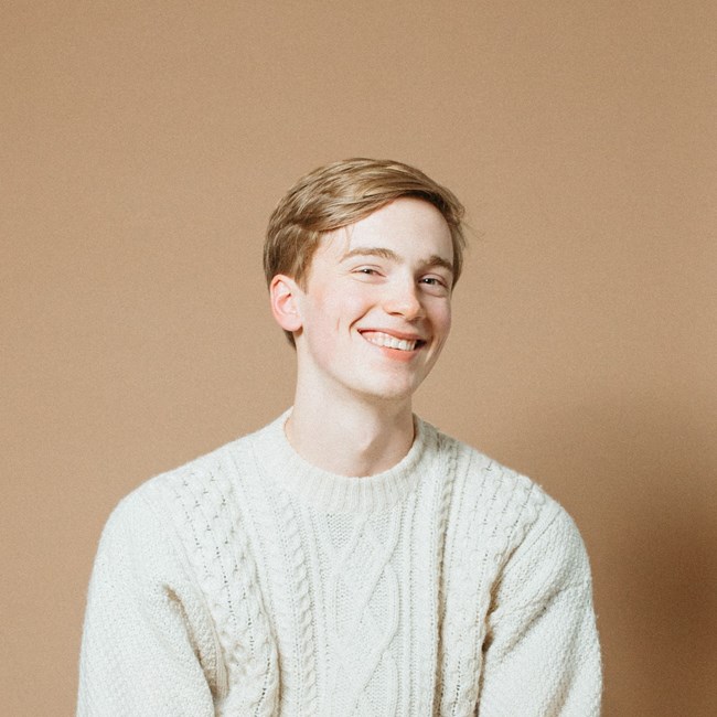 Smiling young man with strawberry blond hair wearing a white sweater Smiling young man with strawberry blond hair wearing a white sweater