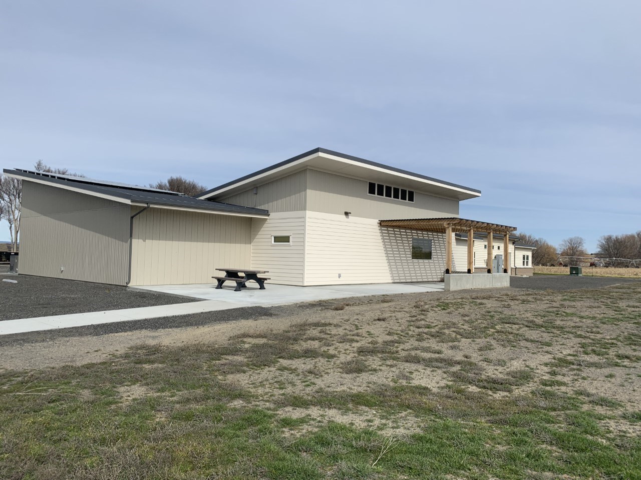 A cream cinderblock building with a wooden patio cover.