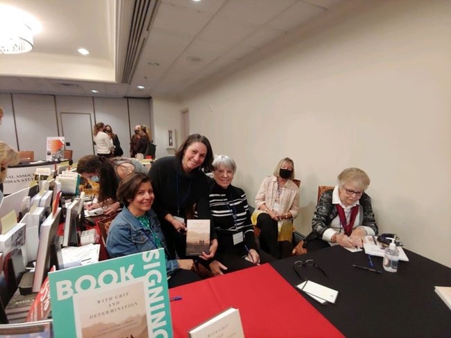 A group of women sitting behind a table signing books