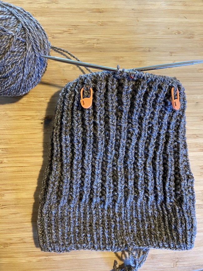 Partially completed knit hat with three stitch markers visible