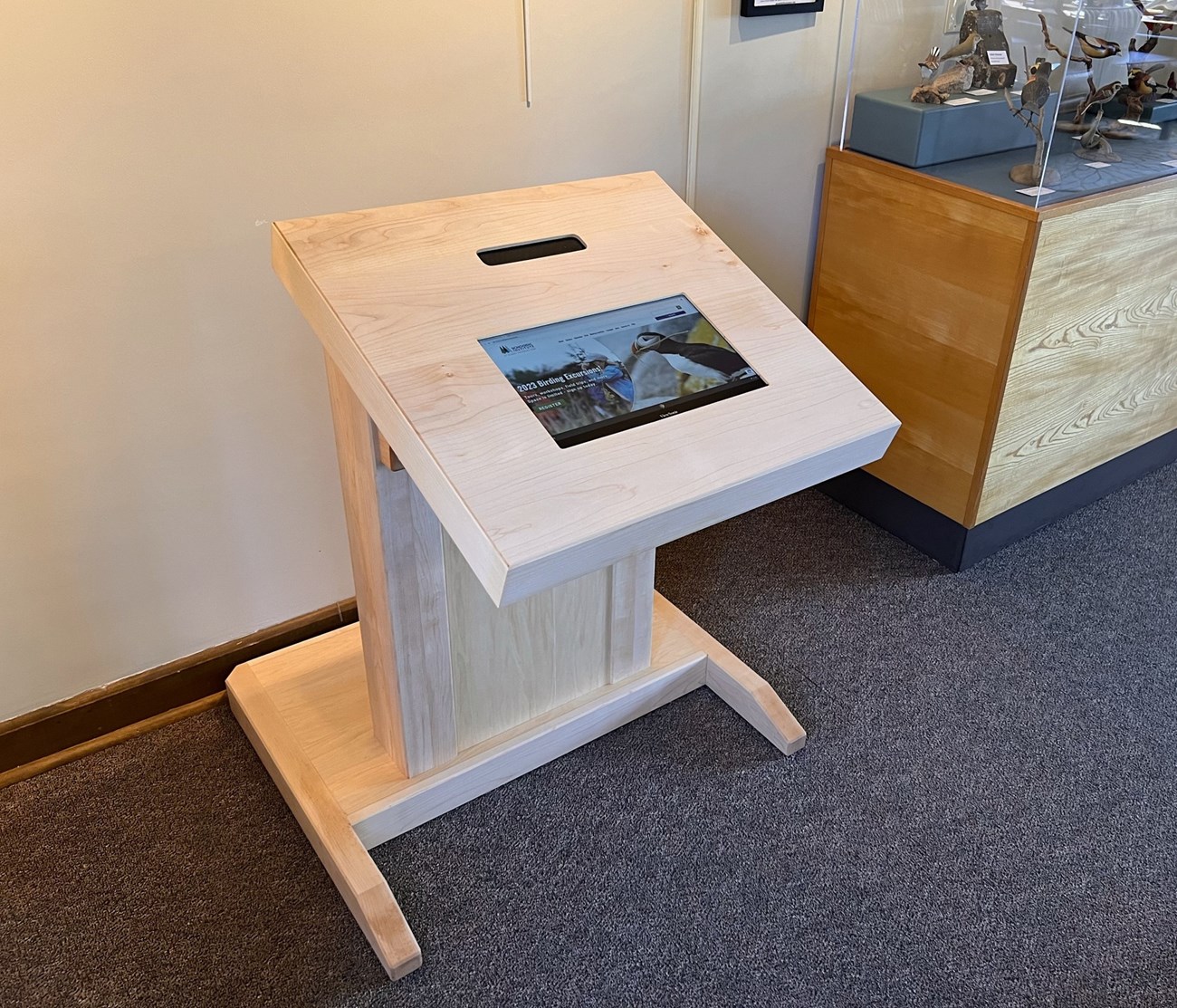 Welcome center display A wooden stand with an inset touch screen. The touch screen displays a program with a photo of a puffin and some text.