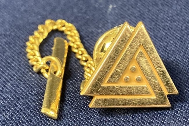 gold tie tack with double triangle and circle design