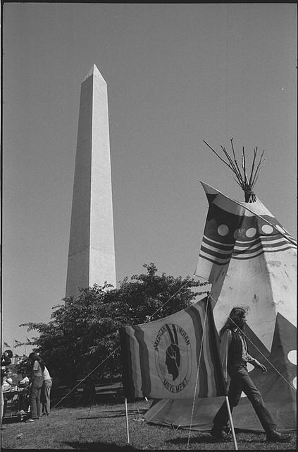 Tipi and flag that reads "American Indian Movement" in front of Washington Monument