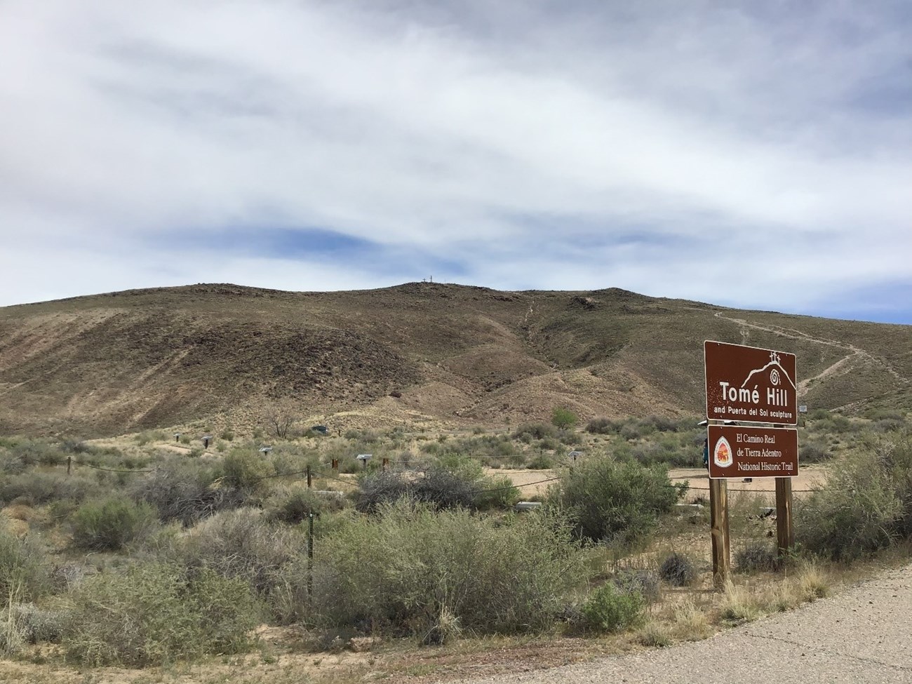 Hill covered in desert brush and El Camino Real de Tierra Adentro sign