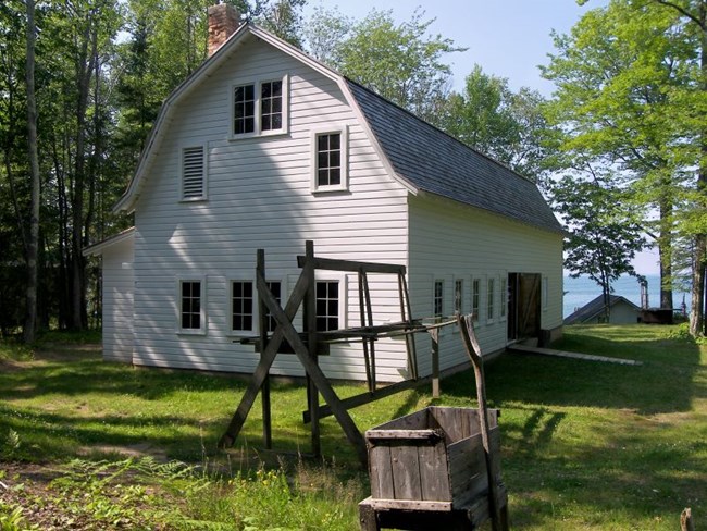 White, barn-shaped building with net drying reel in the foreground.