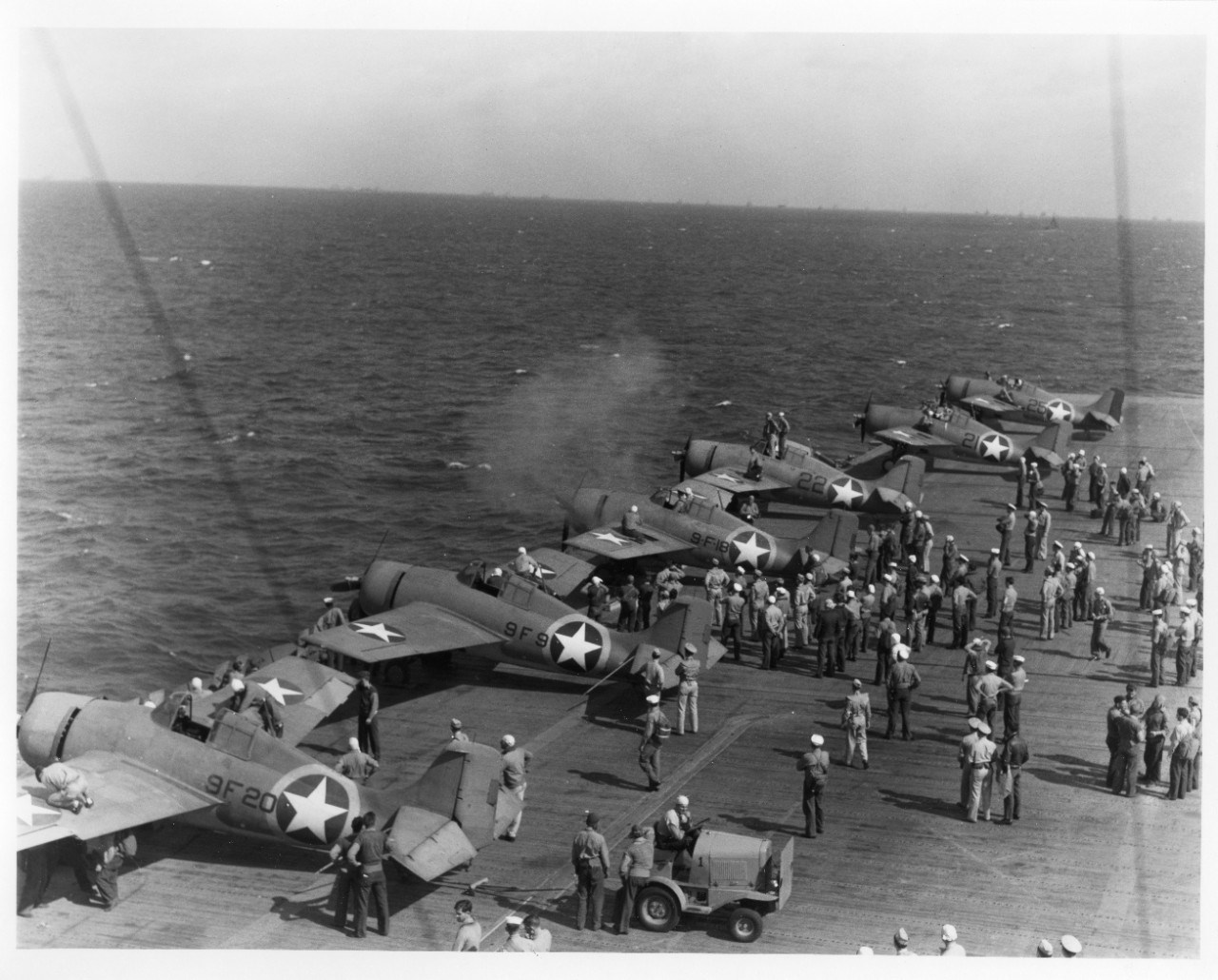 USS Ranger with F4F-4 Wildcat Fighter planes large ship with six planes on deck, people milling about, and vehicles.