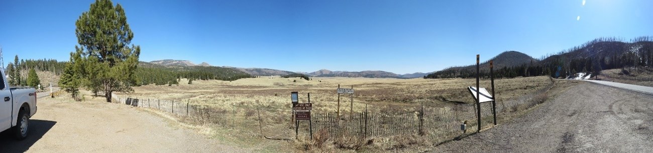 Panorama of a large grassy plain, and mountains in the distance.