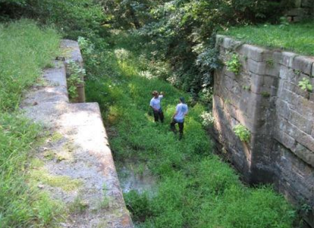 Youth crew in canal prism doing vegetation removal work.