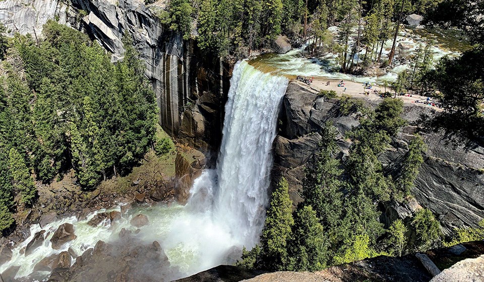Vernal Fall from above with hikers at edge of fall