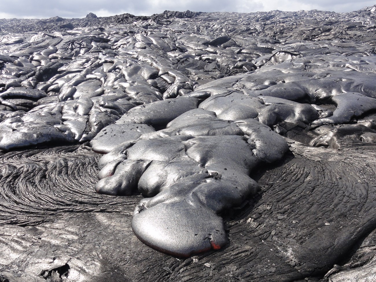 Photo of pāhoehoe toes on an active lava flow.