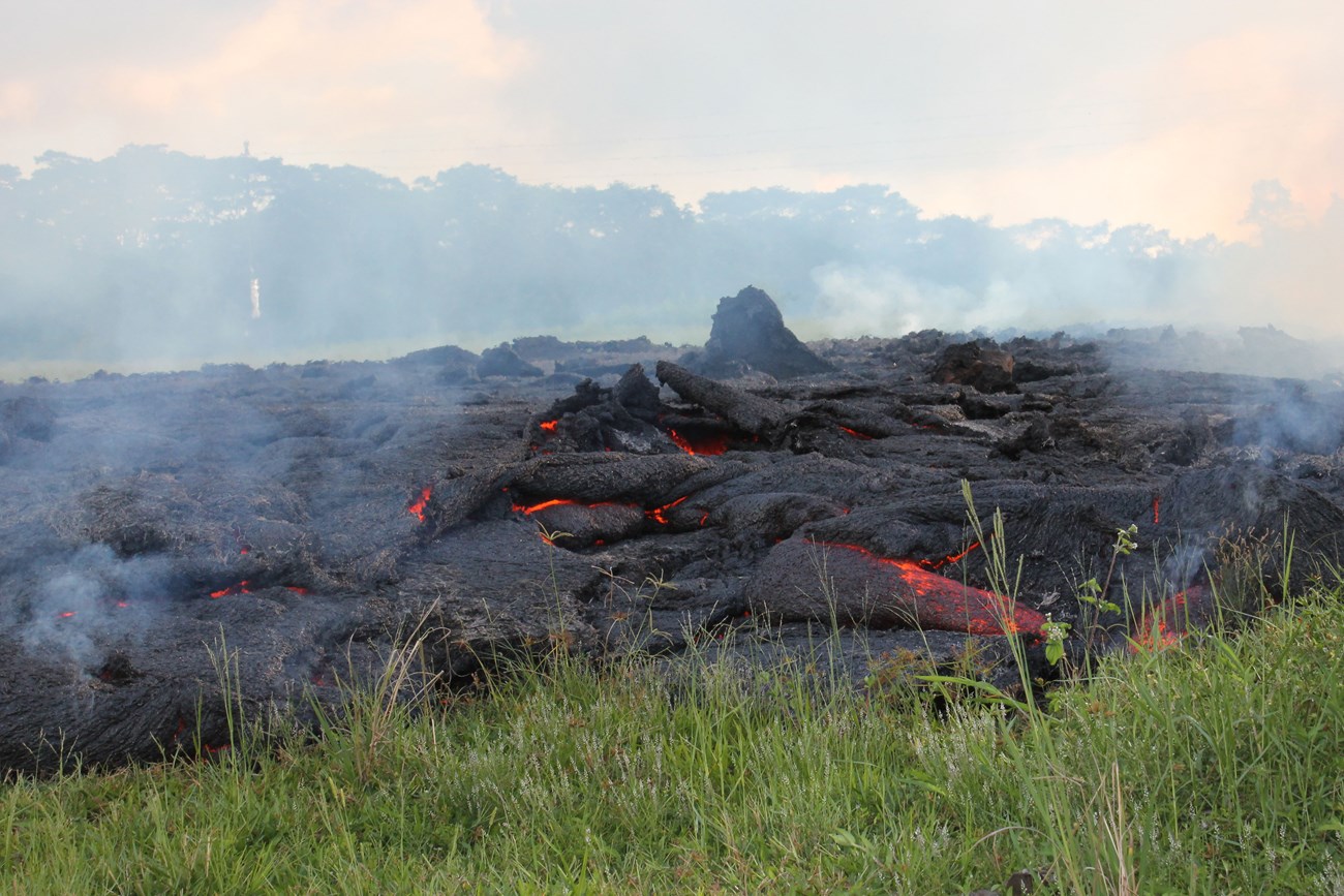 Photo of lava flow with molten lava under cooler slabs of rock.