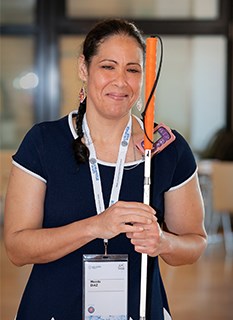 web Wanda Diaz Merced IAU/M. Zamani Woman in dark blue dress with orange and white cane for navigation