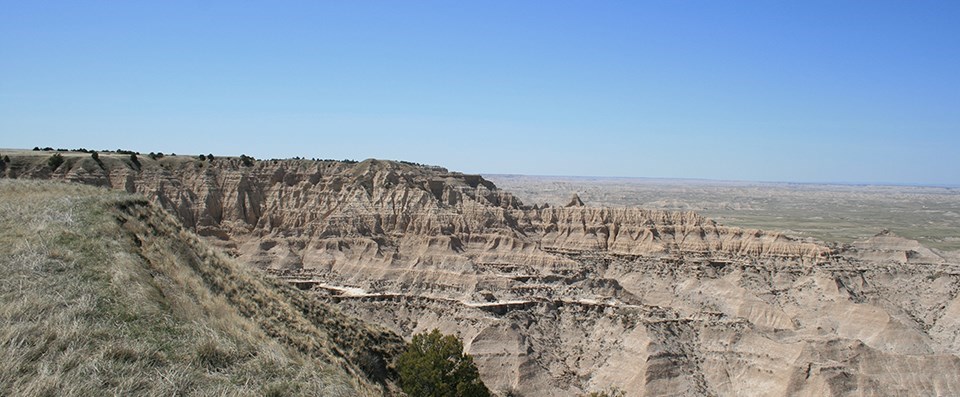 badlands buttes create a high wall, below which prairie spreads out in every direction