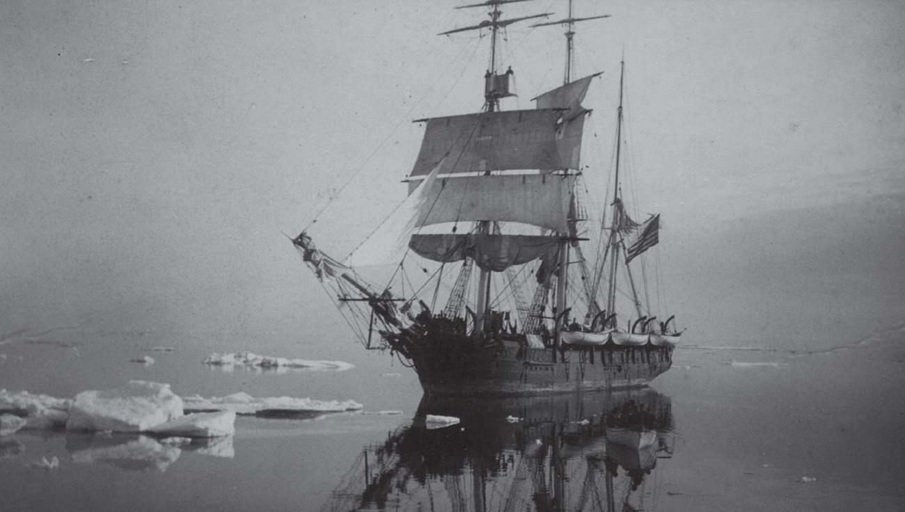 a historic scene of a huge ship with large sails navigating waters with icebergs.