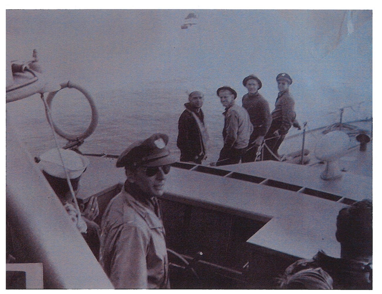 Black and white photo of seven men in uniform on a boat.