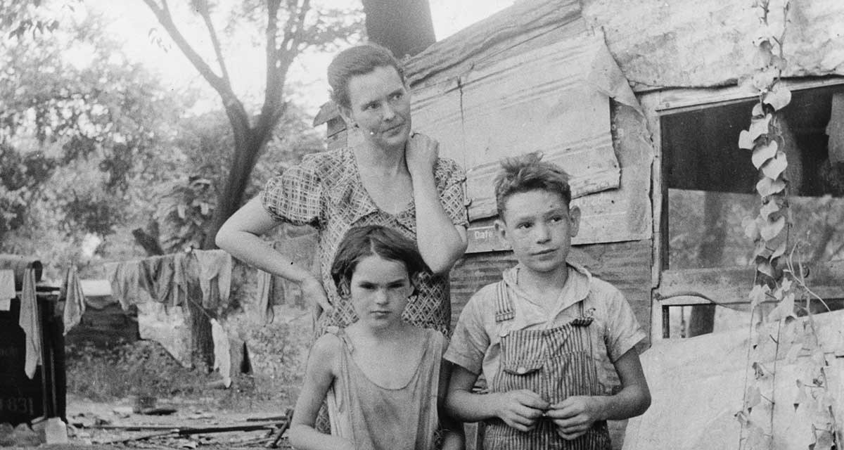 womankids A black and white photo of a woman and kids dressed in raggedy clothes