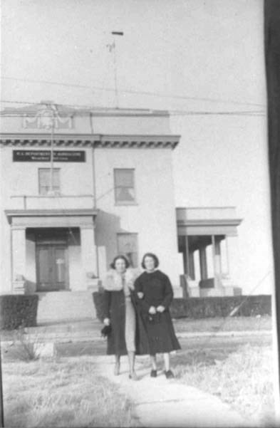 two women pose in front of a building