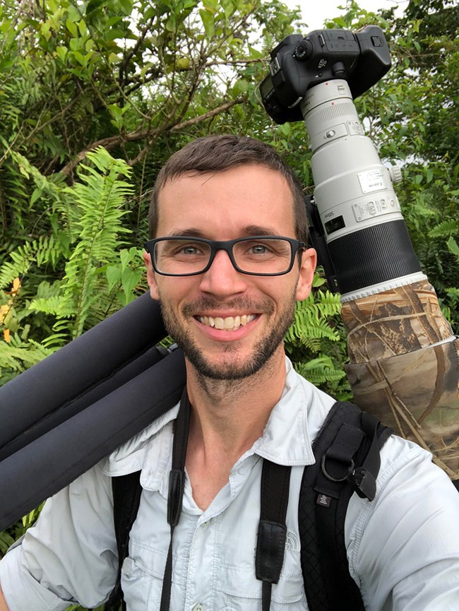 Judd Patterson portrait Data manager Judd Patterson smiles while holding camera equipment.