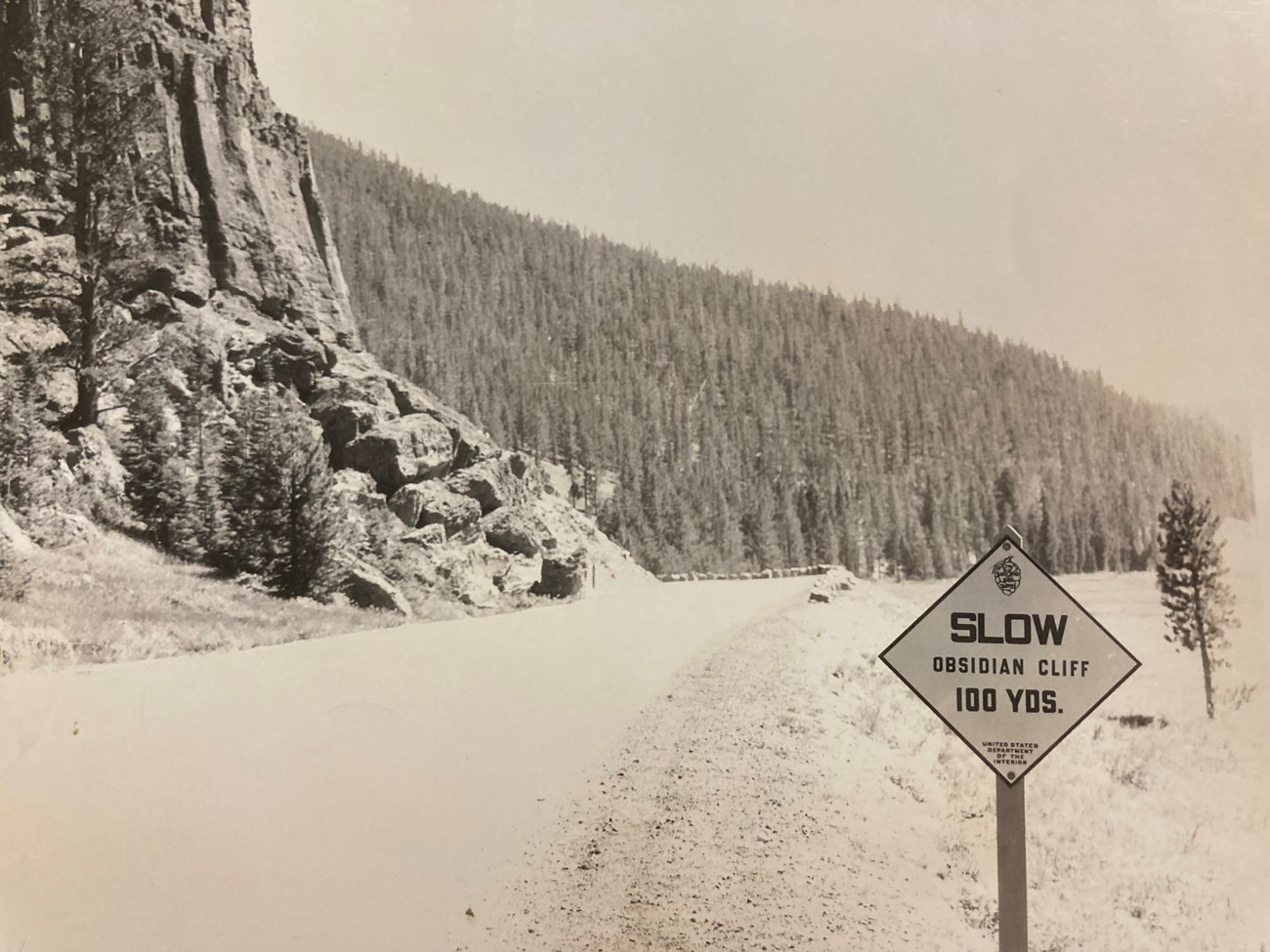 Slow road sign near a large cliff