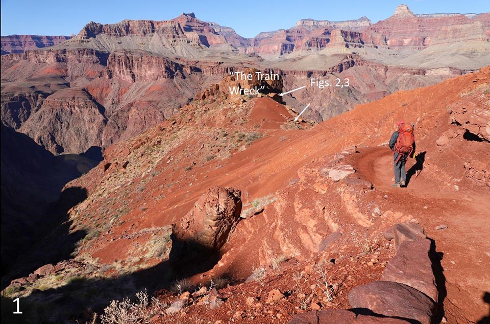 Within a colorful desert landscape, a hiker is walking down a trail through orange-colored soil. A butte in the foreground has superimposed captions: "The Train Wreck," and a reference to Figs 2,3.