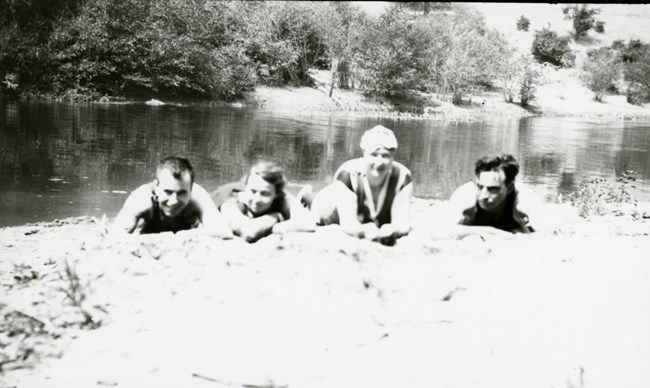 lt= black and white photo of men and women playing in a lake