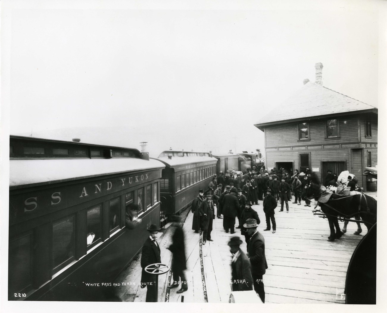 a trail rolling past a station with men standing outside
