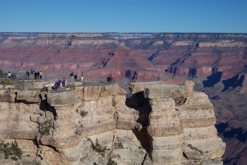 Grand Canyon outcropping with visitors sightseeing on top.