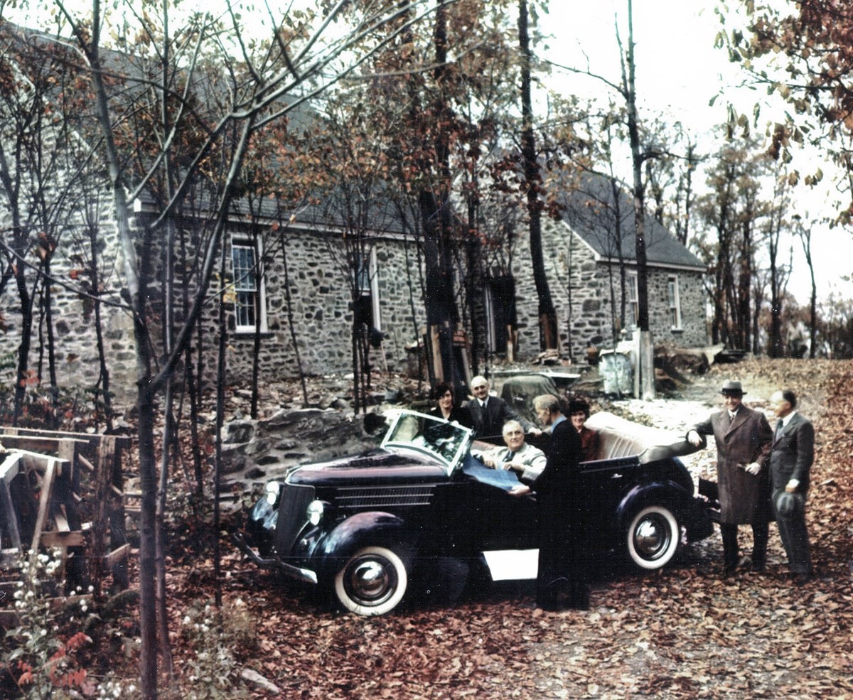 A man in a car with a house under construction in the background.