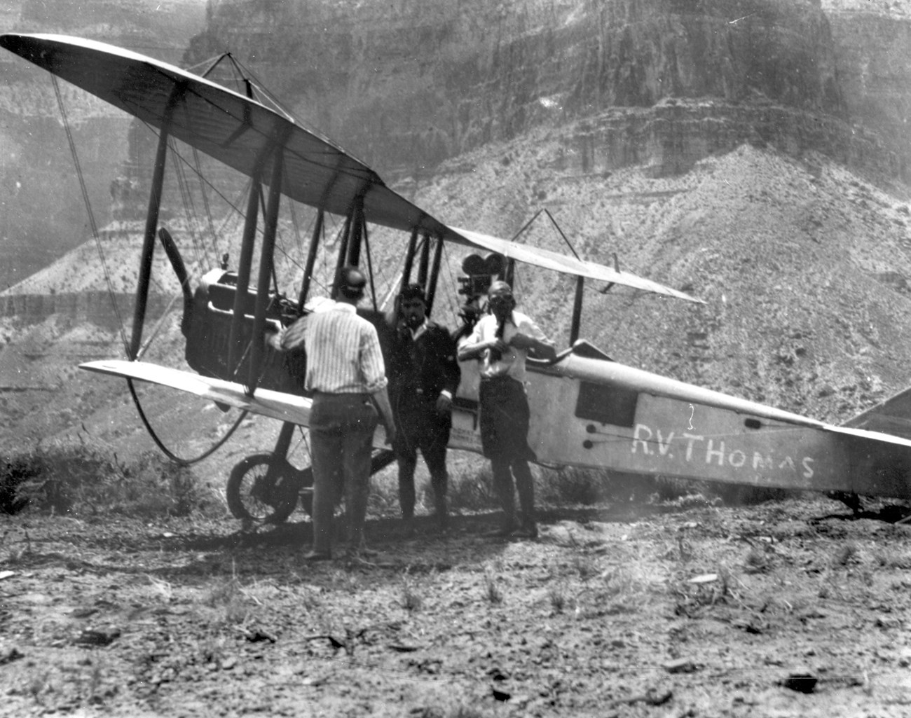 Three people standing next to a biplane.