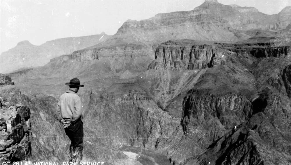 Man in a wide-brimmed facing Grand Canyon's landscape.