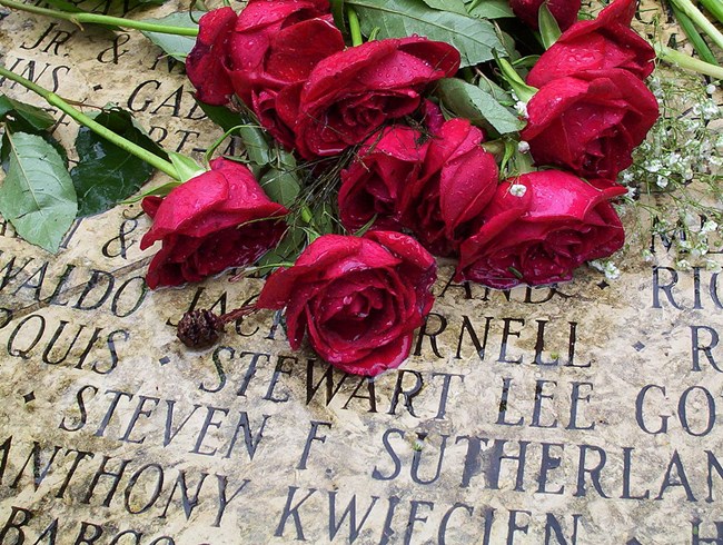 Red roses lie on names engraved in stone at the AIDS Memorial