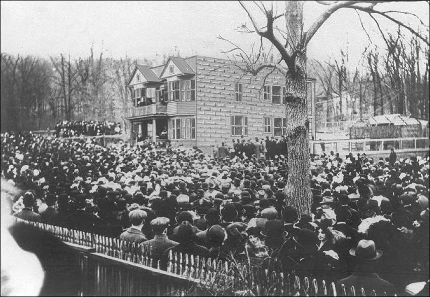 Crowd of people outside a house.