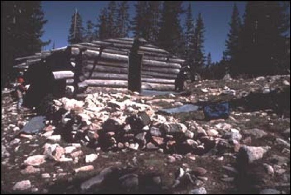 Photo of a log cabin on a rocky hill. (National Park Service, Western Archeological and Conservation Center Photos)
