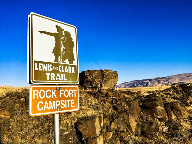 1116a sign that says Rock Fort campsite and rocks in the background