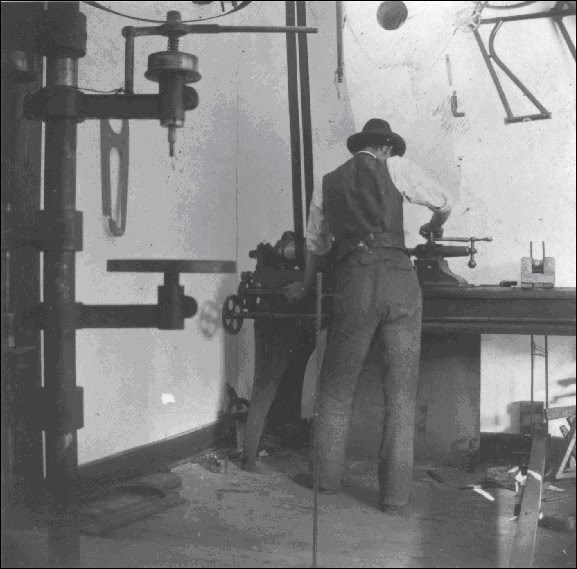 A man working in a workshop with his back turned toward the camera.