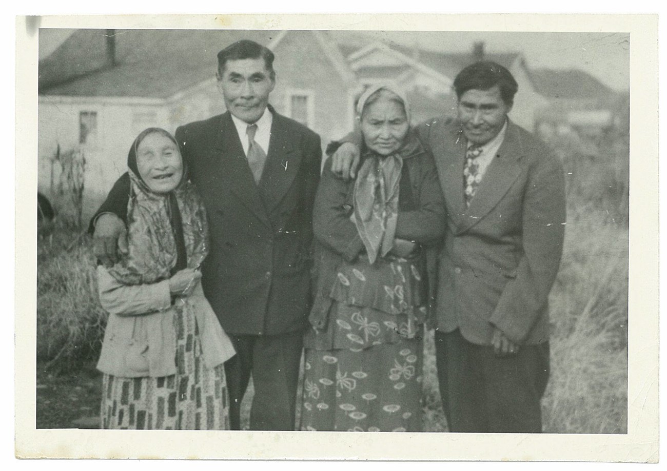 Black and white photo of two couples, the men with their arms around the women.
