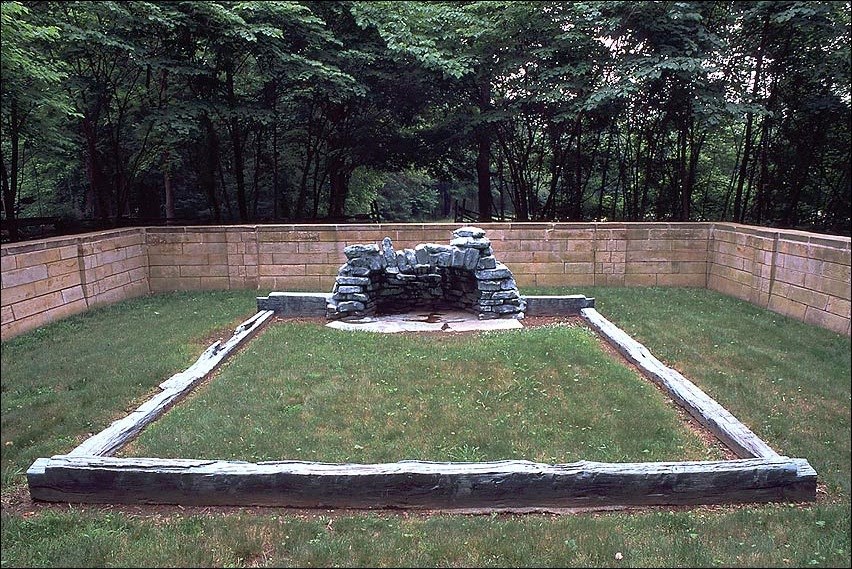 Stone memorial surrounded by grass and a brick wall. National Park Service photo.