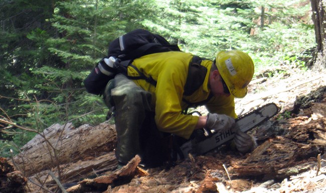 A firefighter works on a chainsaw.