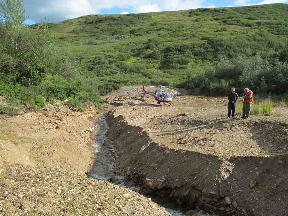 Two researchers meet along a river channel.