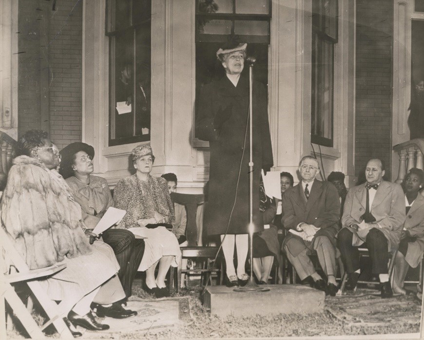Woman speaking in front of group of seated women. Woman speaking in front of group of seated women.