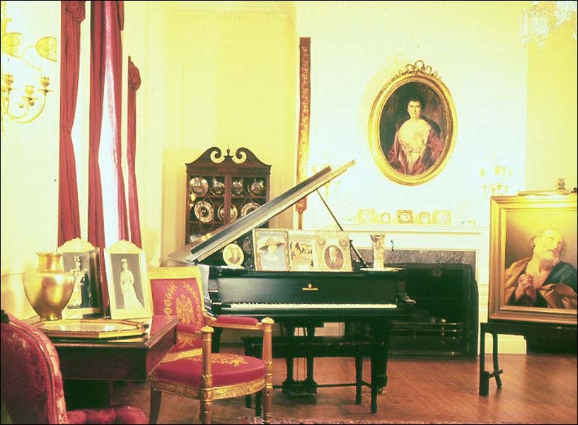 Wilson's drawing room with piano and chairs.