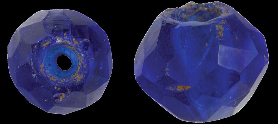 End and side view of a dark blue spherical bead with many ground facets.