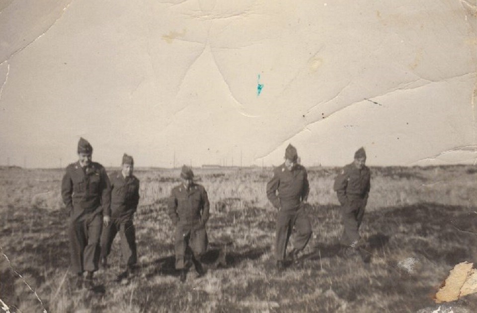 Men in National Guard Uniforms Five men in uniforms walking across a grassy field.