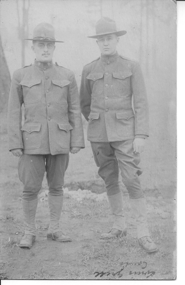 Black and white photograph of two men wearing World War I Army uniforms.