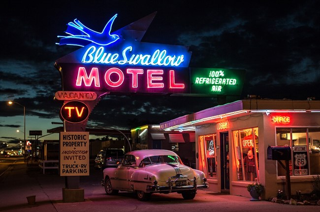 Blue Swallow Motel at night with neon-light sign. Photo by Sylvain L., CC BY 2.0