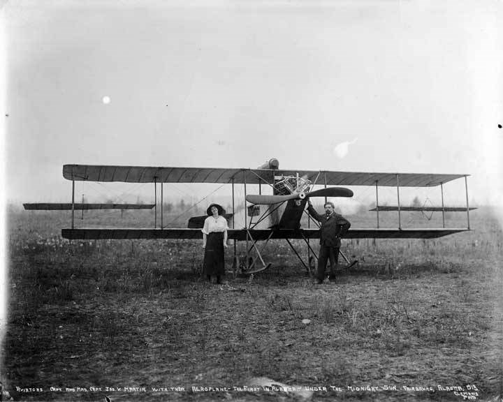 two people standing in front of airplane on ground